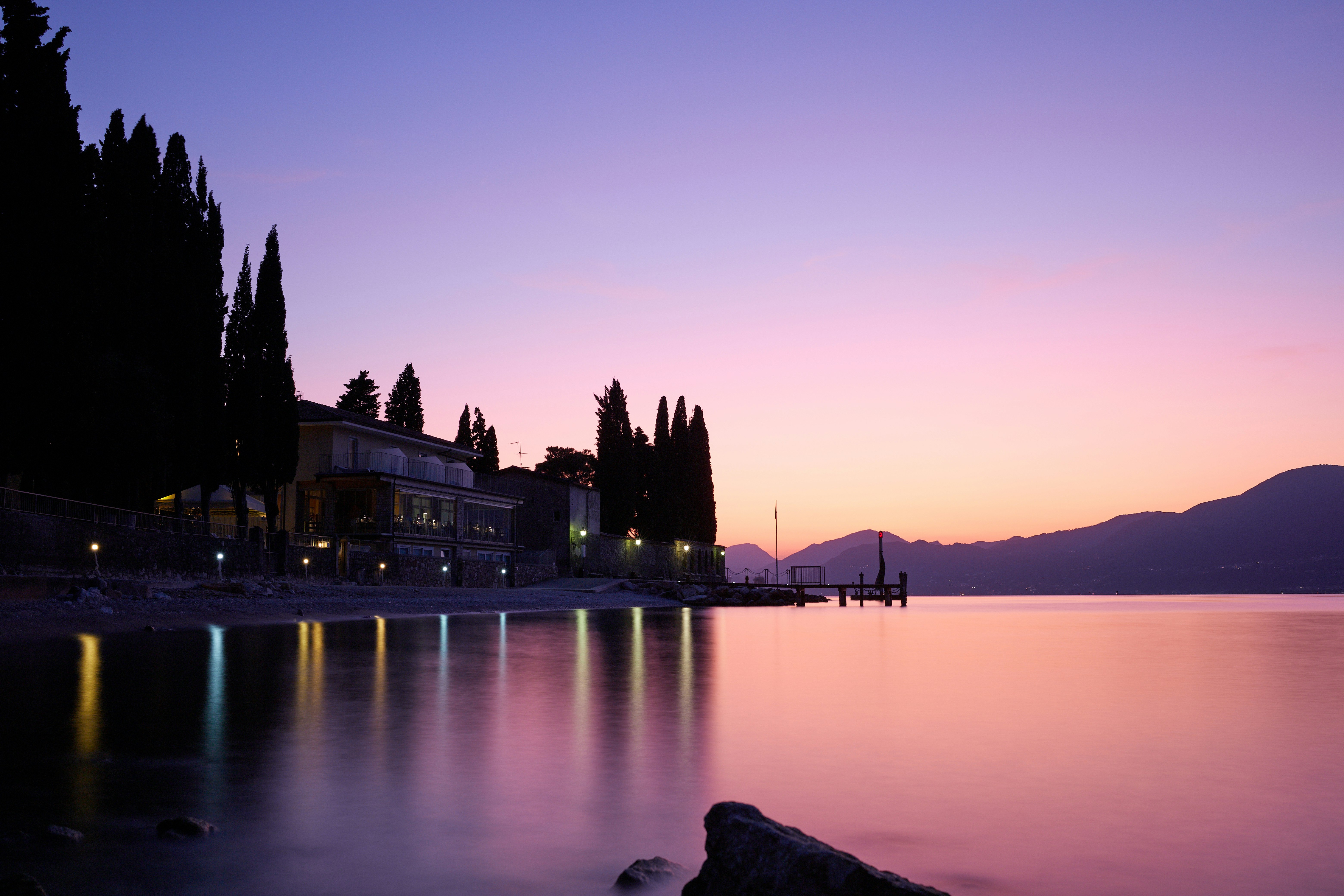 silhouette of building near body of water during sunset